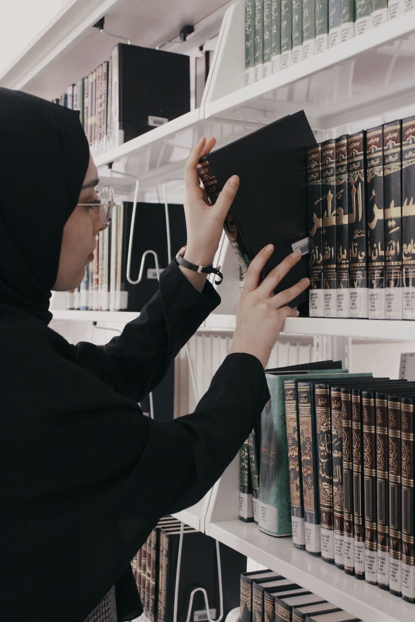 A reader returning a bound classical text to a library shelf.